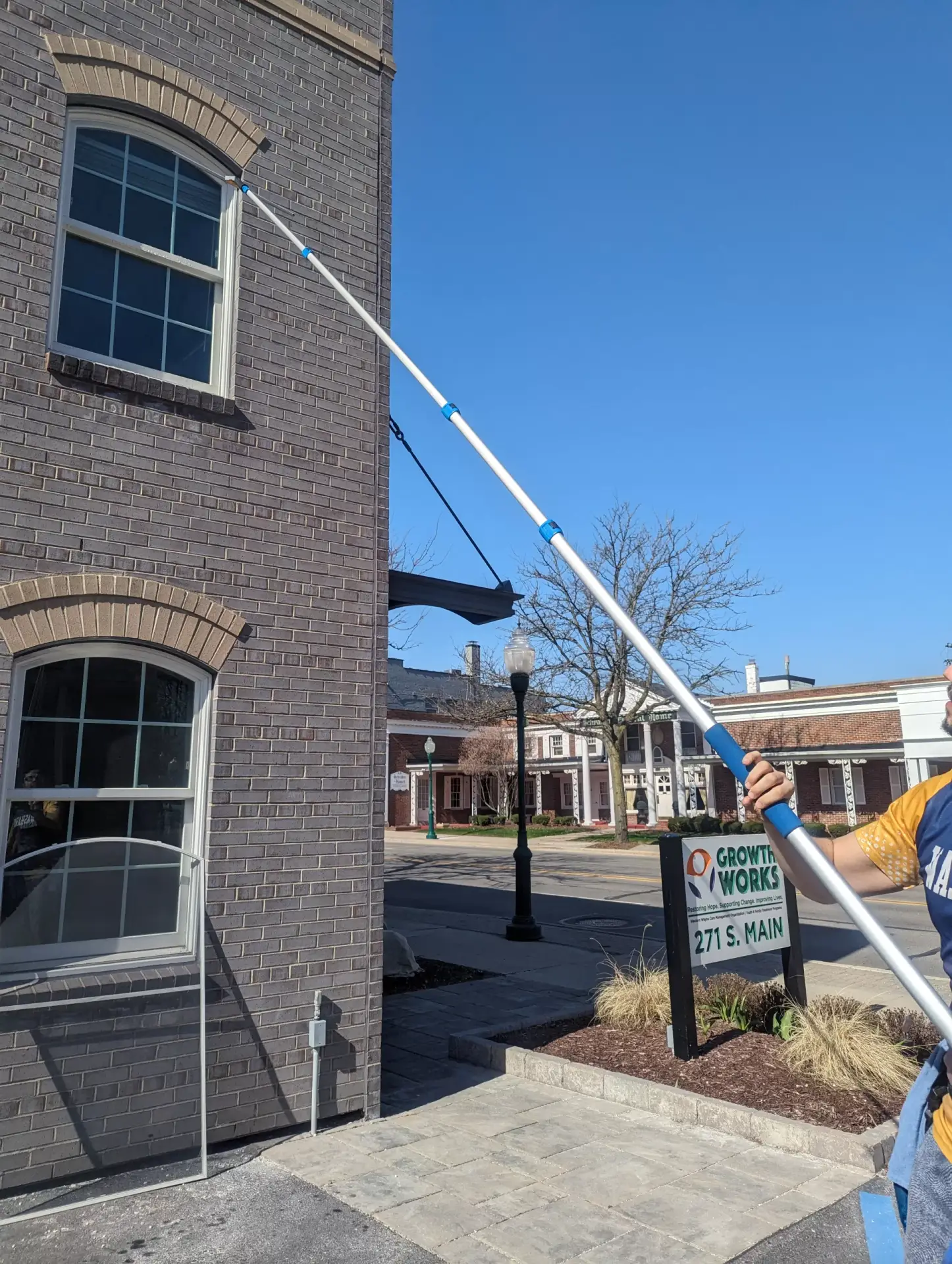 WashAway technician cleaning an upper commercial window with a water-fed pole
